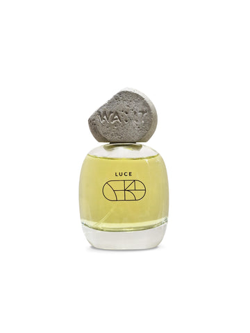 A bottle of LUCE Eau de Parfum with a yellowish liquid and a concrete cap, displayed against a white background.