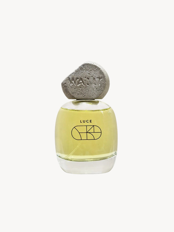 A bottle of LUCE Eau de Parfum with a yellowish liquid and a concrete cap, displayed against a white background.