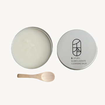 Cleansing balm in a tin with a wooden spoon on a white background