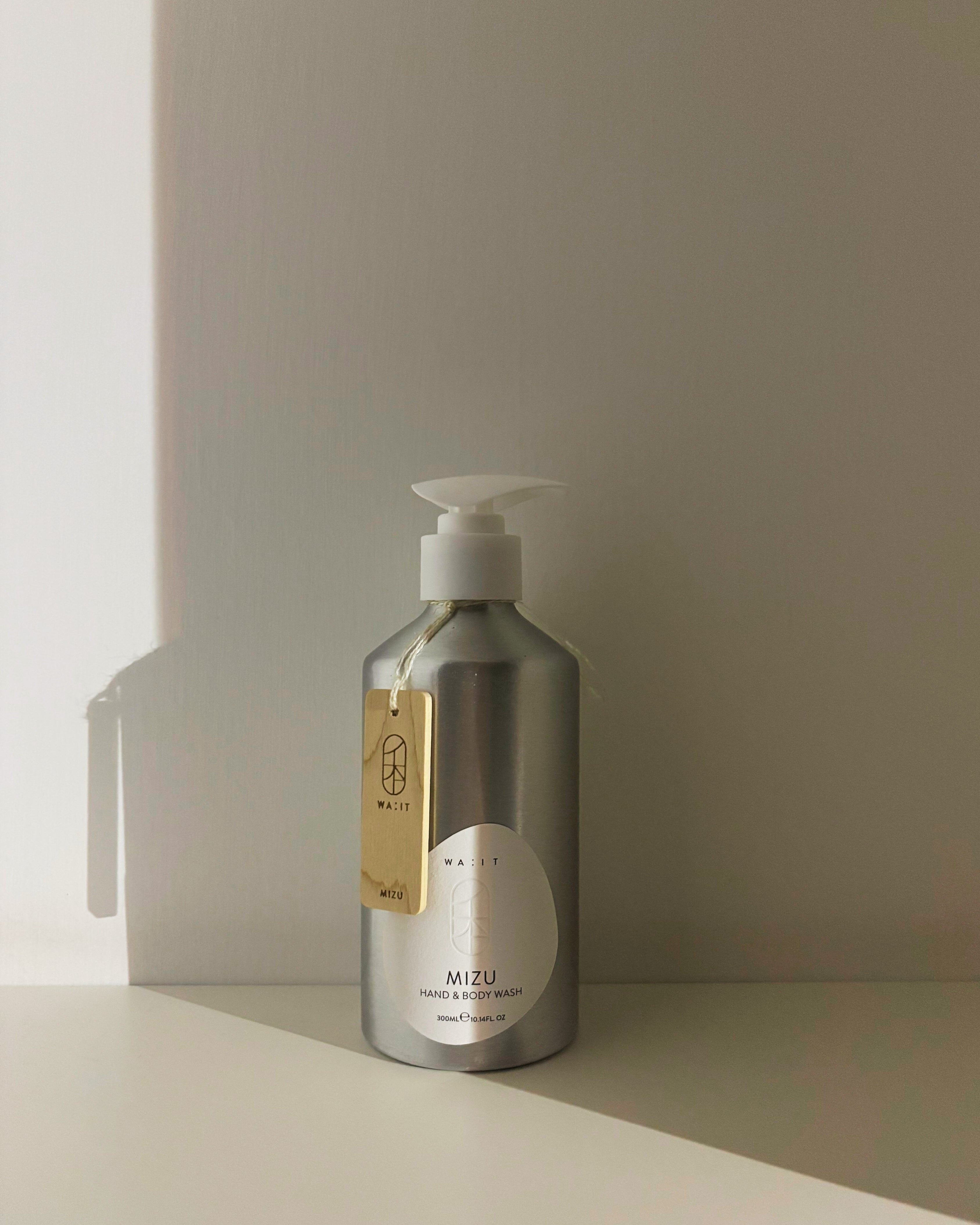 Silver bottle with pump and gold label on a light surface with a neutral background